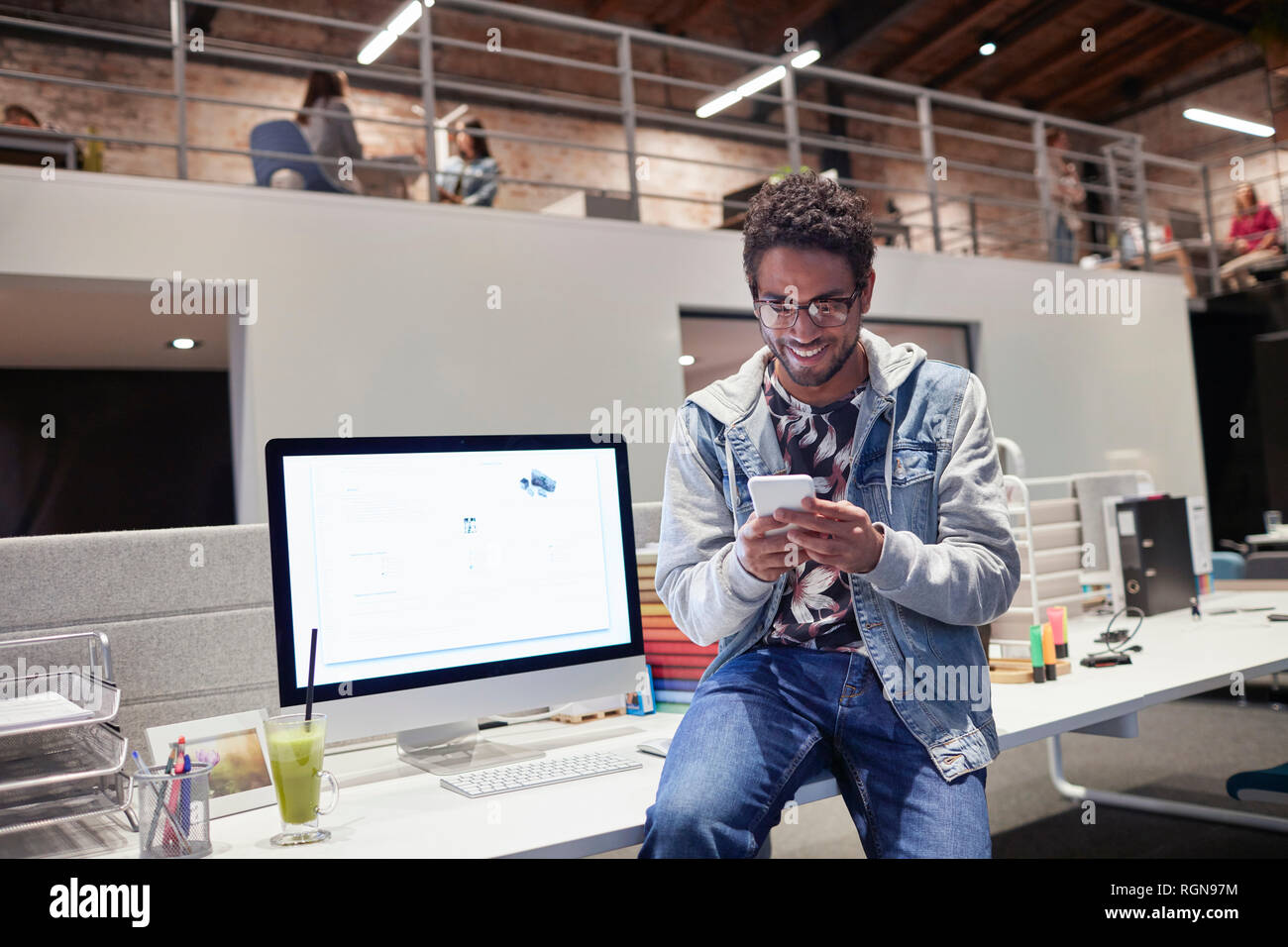 Young man working in creative start-up company, using smartphone Stock Photo