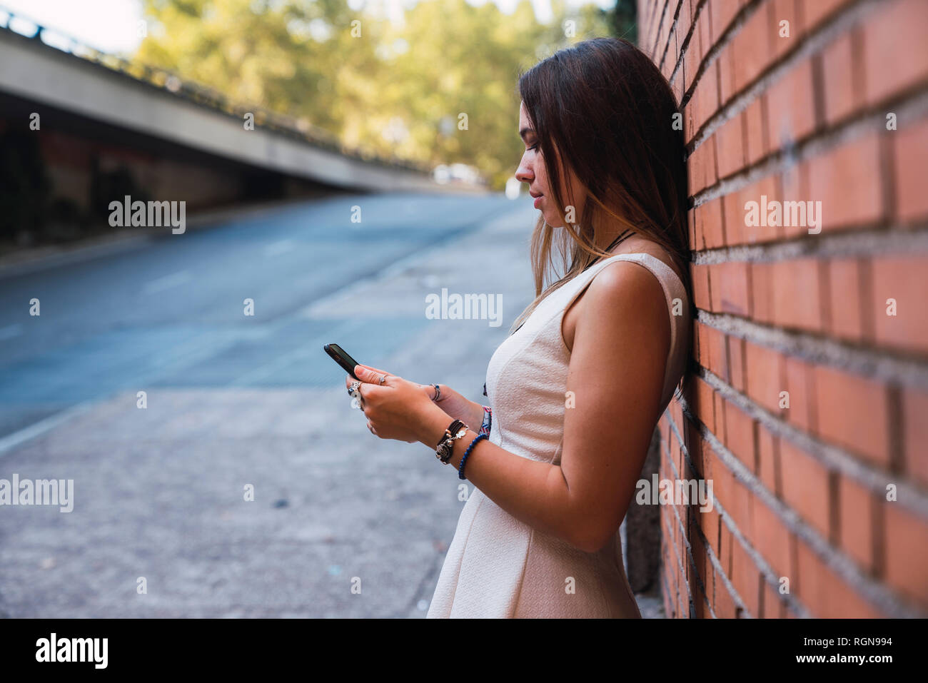 Young woman in front of a brick wall using smartphone Stock Photo
