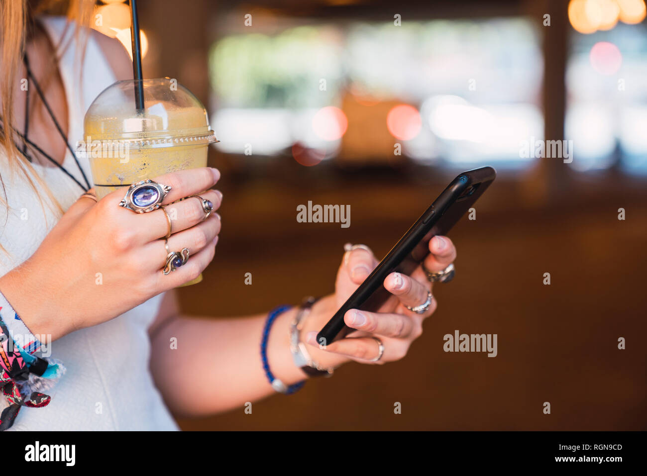Young woman using smartphone and drinking juice Stock Photo