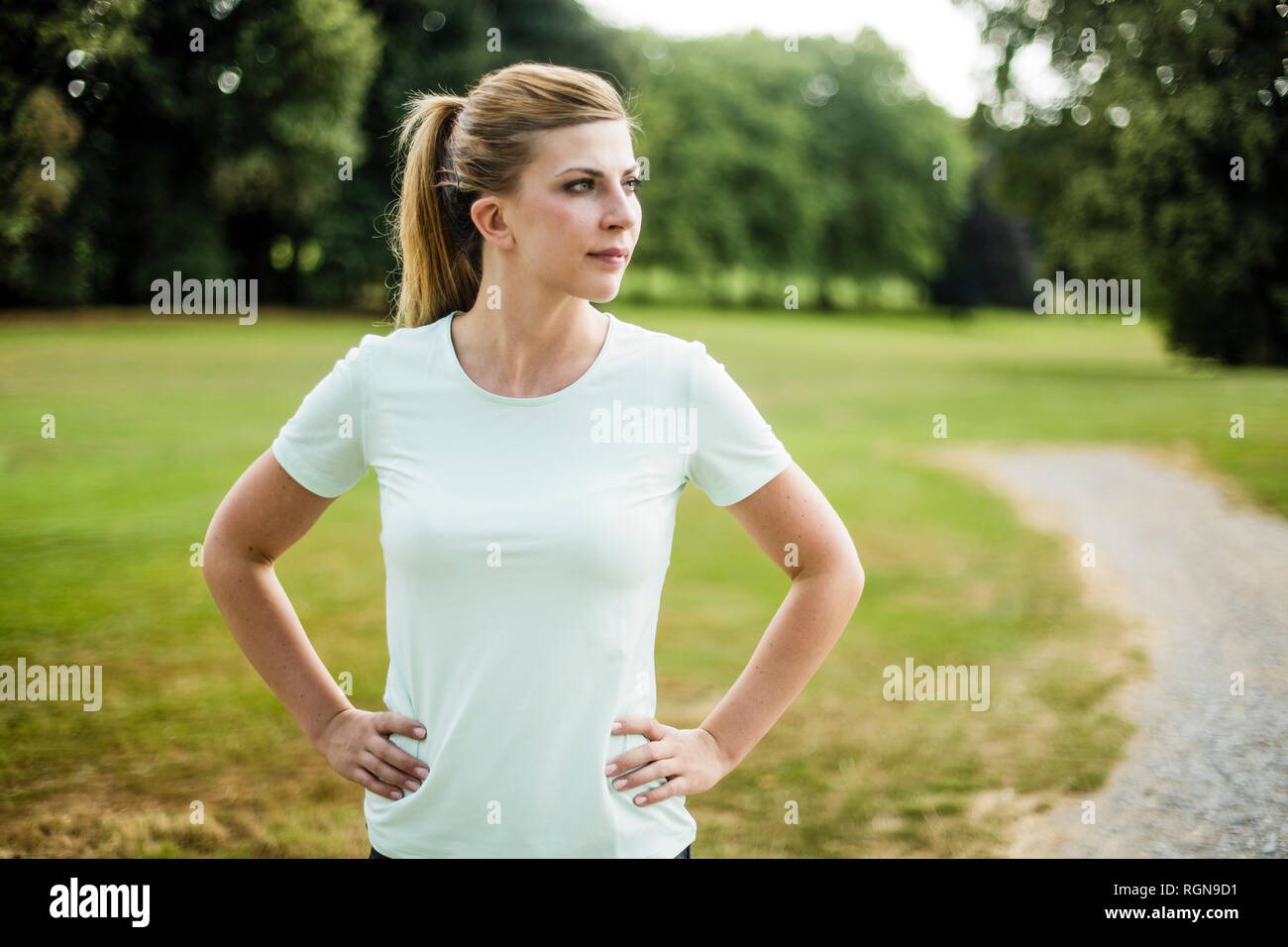Sportive young woman standing in a park looking sideways Stock Photo