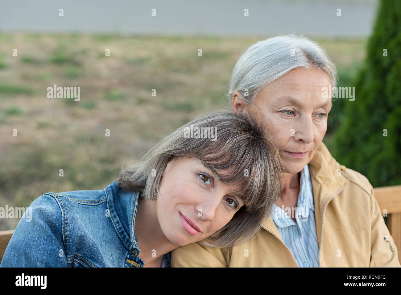 Portrait of mature woman sitting on bench with her mother outdoors Stock Photo