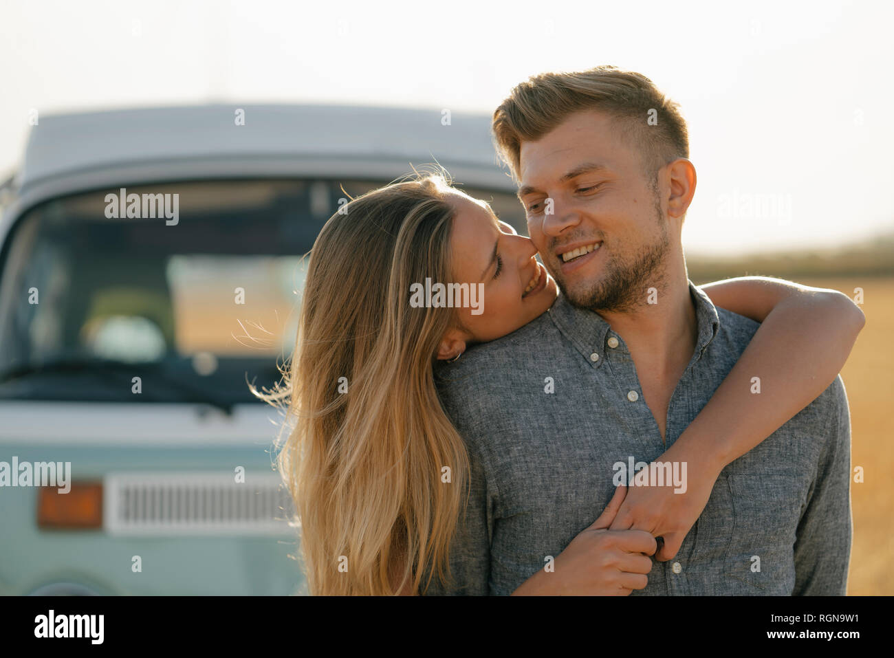 Happy couple hugging at camper van in rural landscape Stock Photo