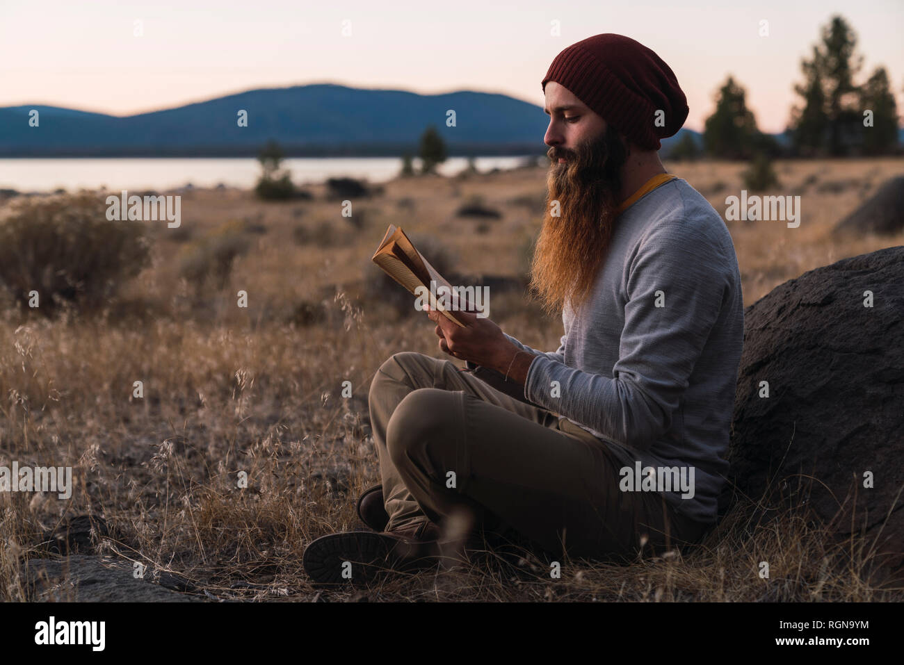 USA, North California, bearded young man reading a book near Lassen Volcanic National Park Stock Photo