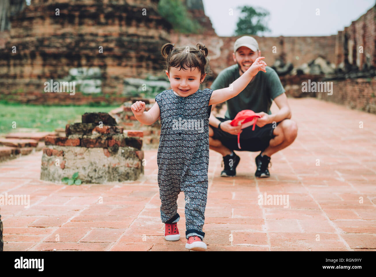 Thailand, Ayutthaya, Father observing his baby girl walking in the ancient ruins of a temple at Wat Mahathat Stock Photo