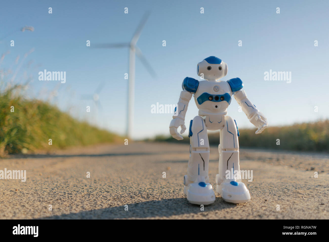 Robot standing on field path at a wind farm Stock Photo