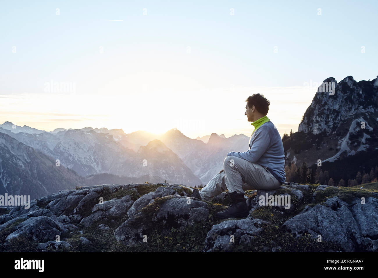 Austria, Tyrol, Rofan Mountains, hiker sitting on rocks at sunset Stock Photo