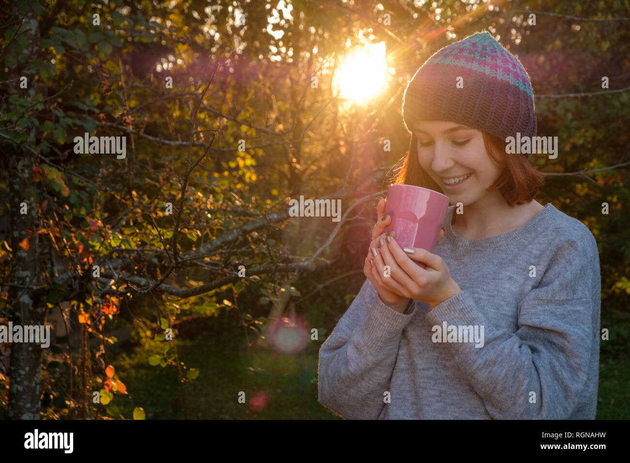 Portrait of smiling teenage girl drinking tea outdoors in autumn Stock Photo