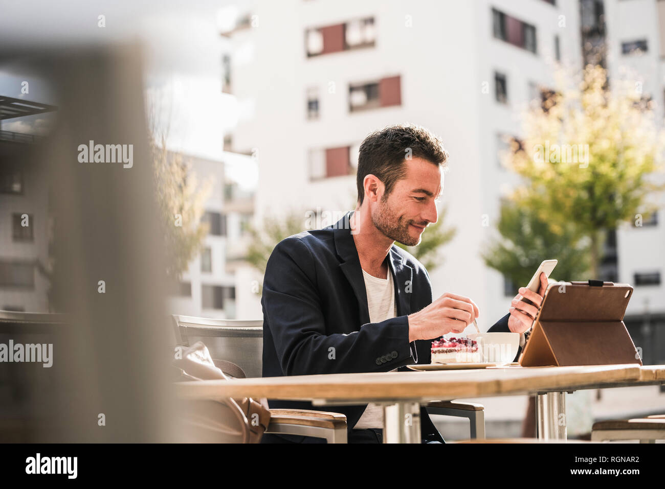 Businessman sitting in cafe, drinking coffee, using smartphone Stock Photo