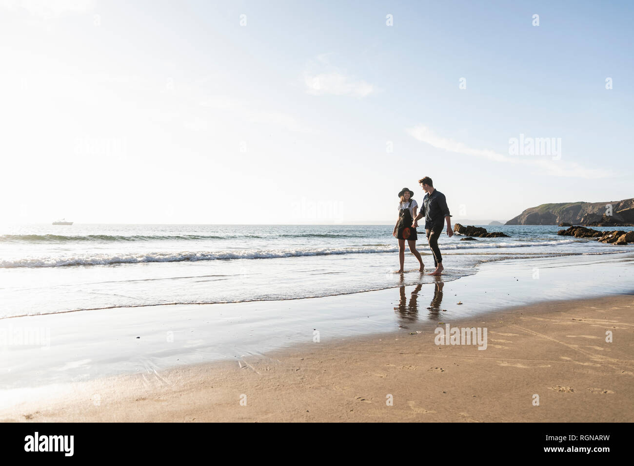 France, Brittany, young couple walking hand in hand at the beach Stock Photo