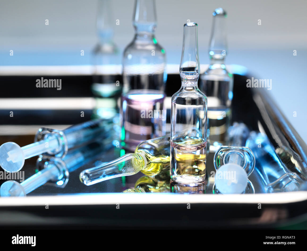 Ampules and phials containing a drug dose next to syringes on a surgical tray Stock Photo