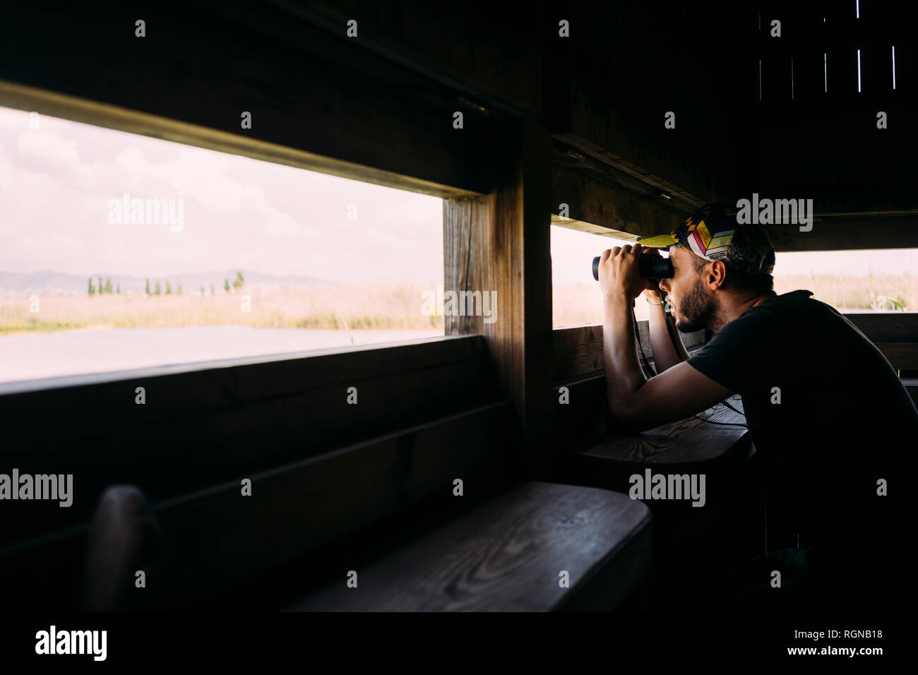 Man birdwatching with binoculars from a viewing tower Stock Photo