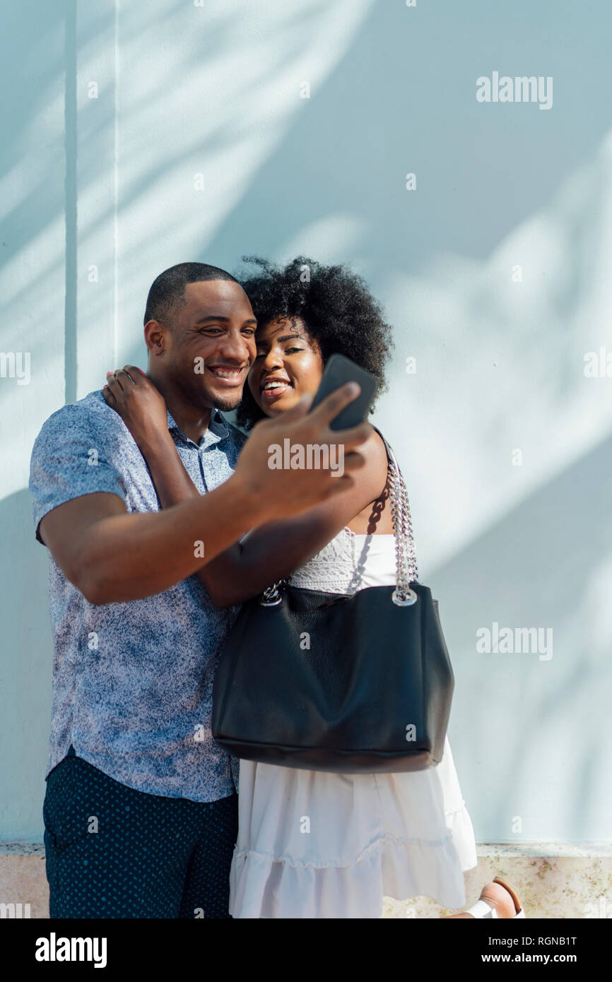 Smiling young couple embracing and taking a selfie Stock Photo