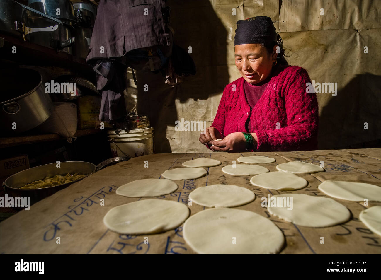 A local woman working in a traditional kitchen, preparing the local dish Momo Stock Photo
