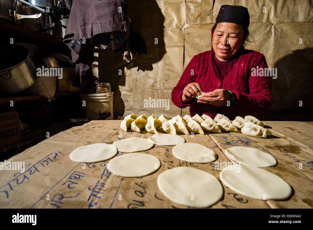 A local woman working in a traditional kitchen, preparing the local dish Momo Stock Photo
