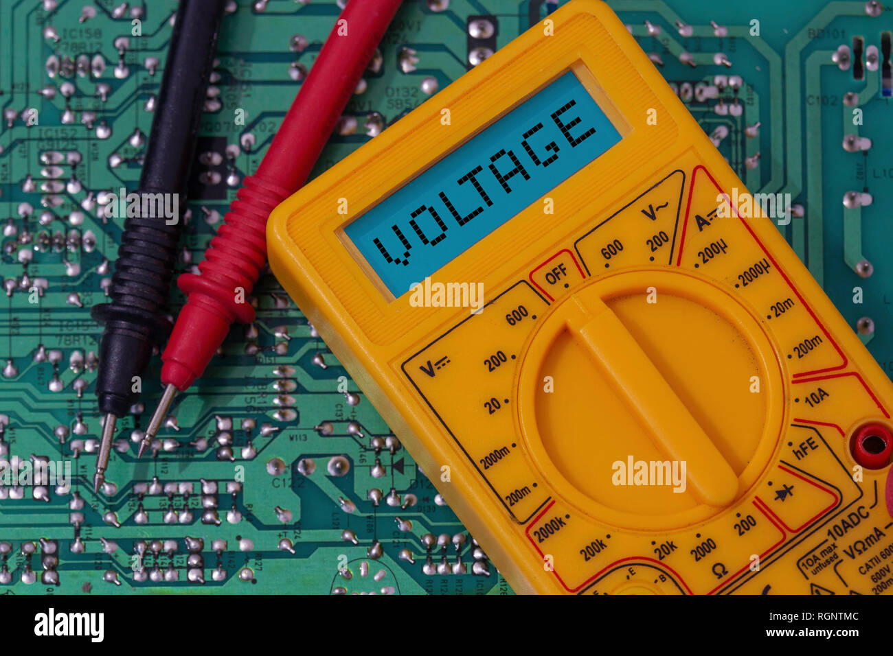 Digital multimeter multitester on a circuit board with the word voltage