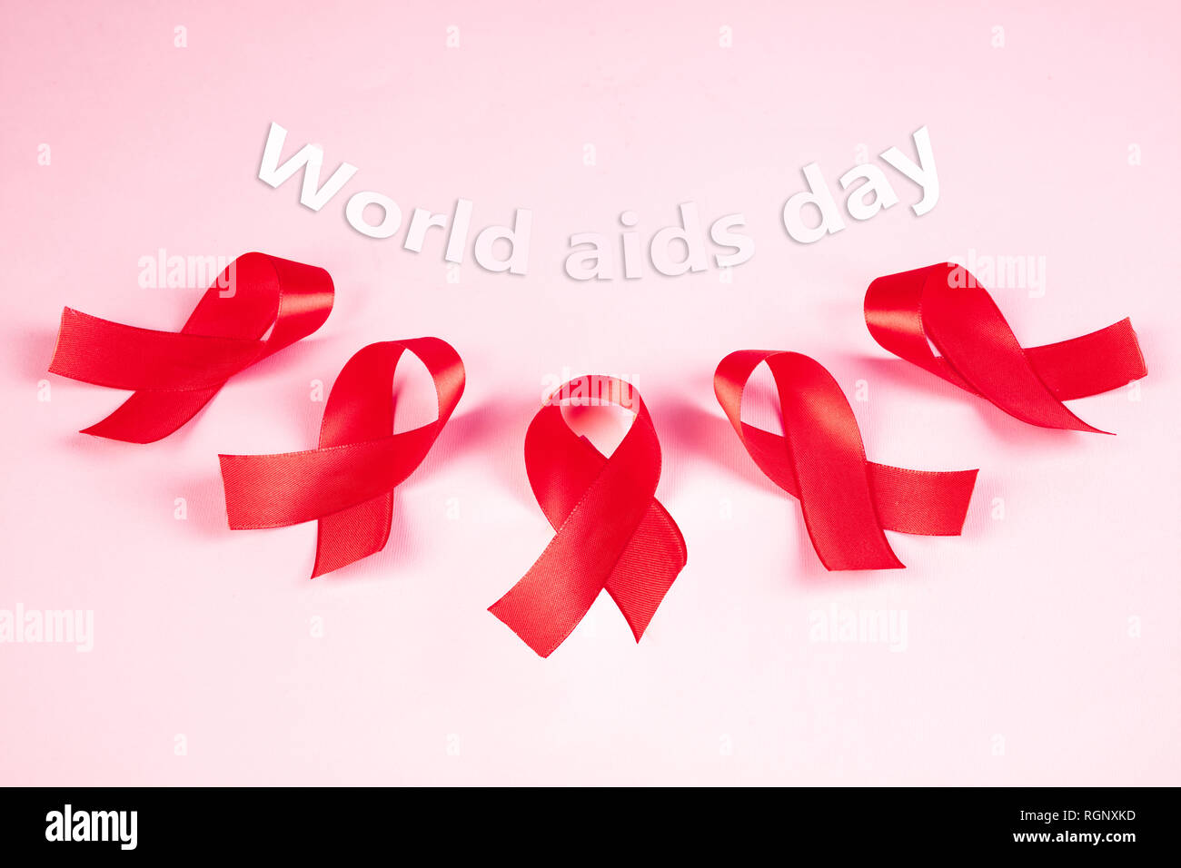 Aids Awareness Sign Red Ribbons on pink background . World Aids Day
