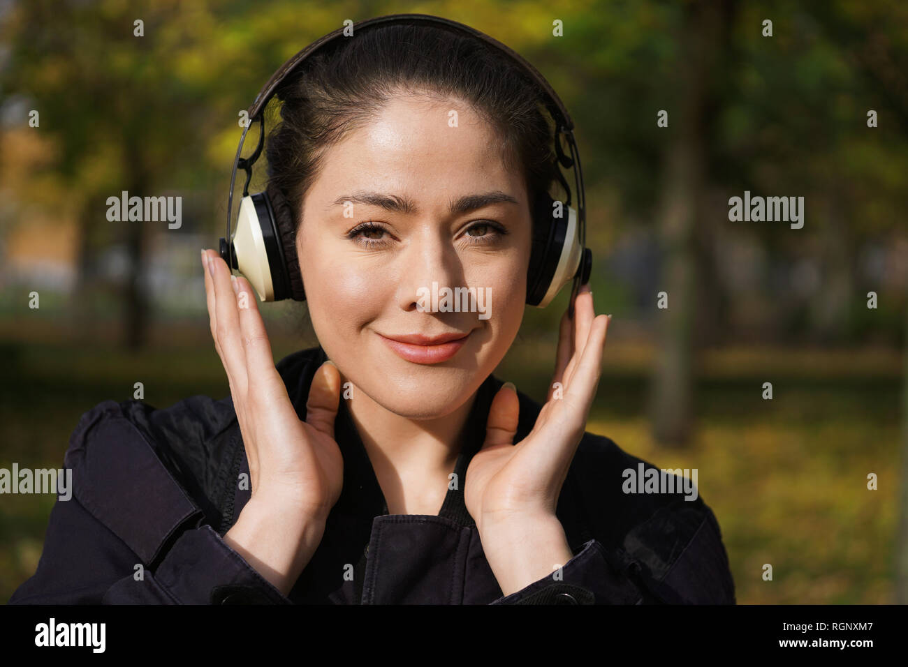 young woman listening to music with cordless headphones outside Stock Photo
