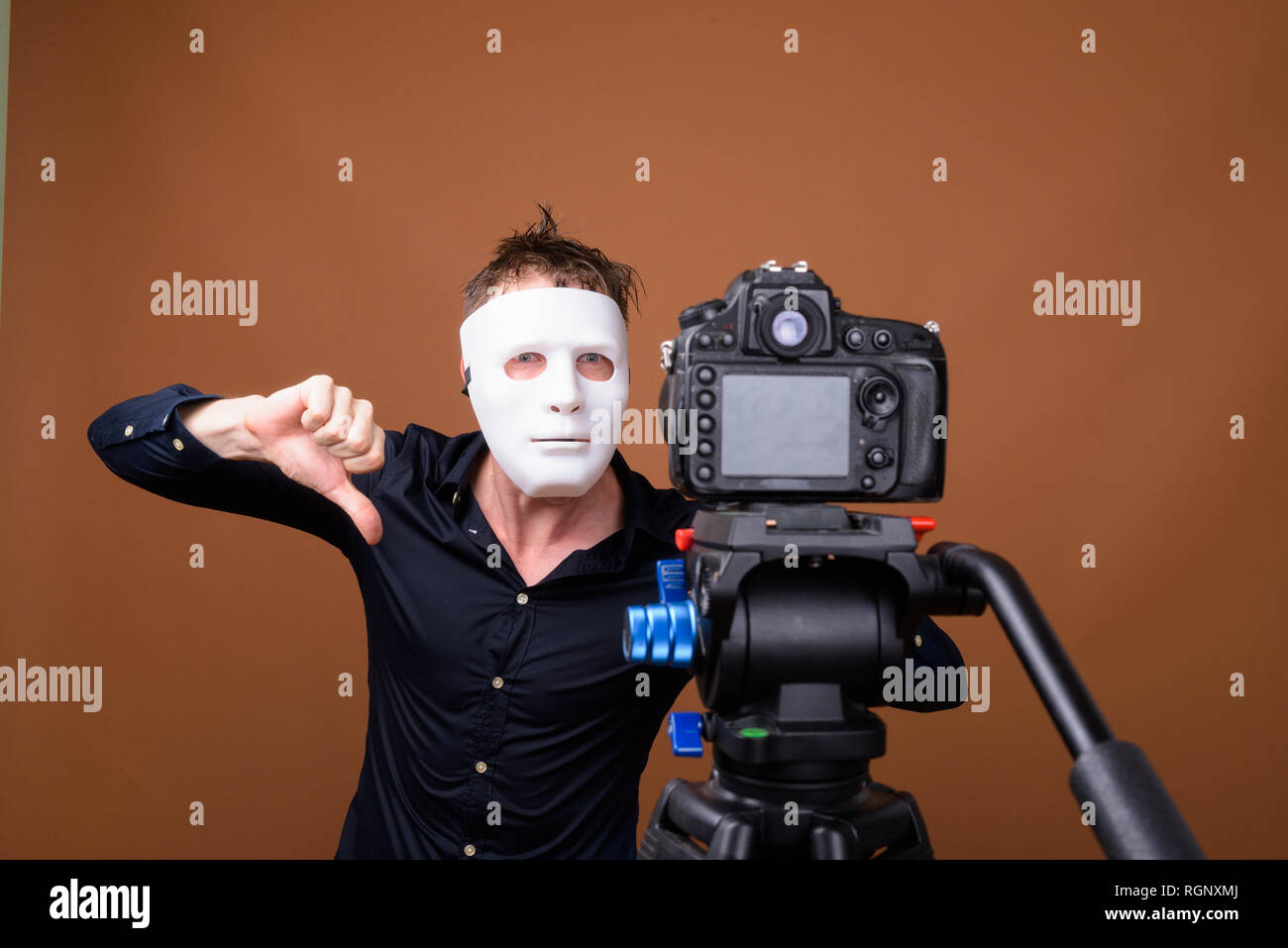 Young man wearing mask while vlogging and showing thumb down Stock Photo