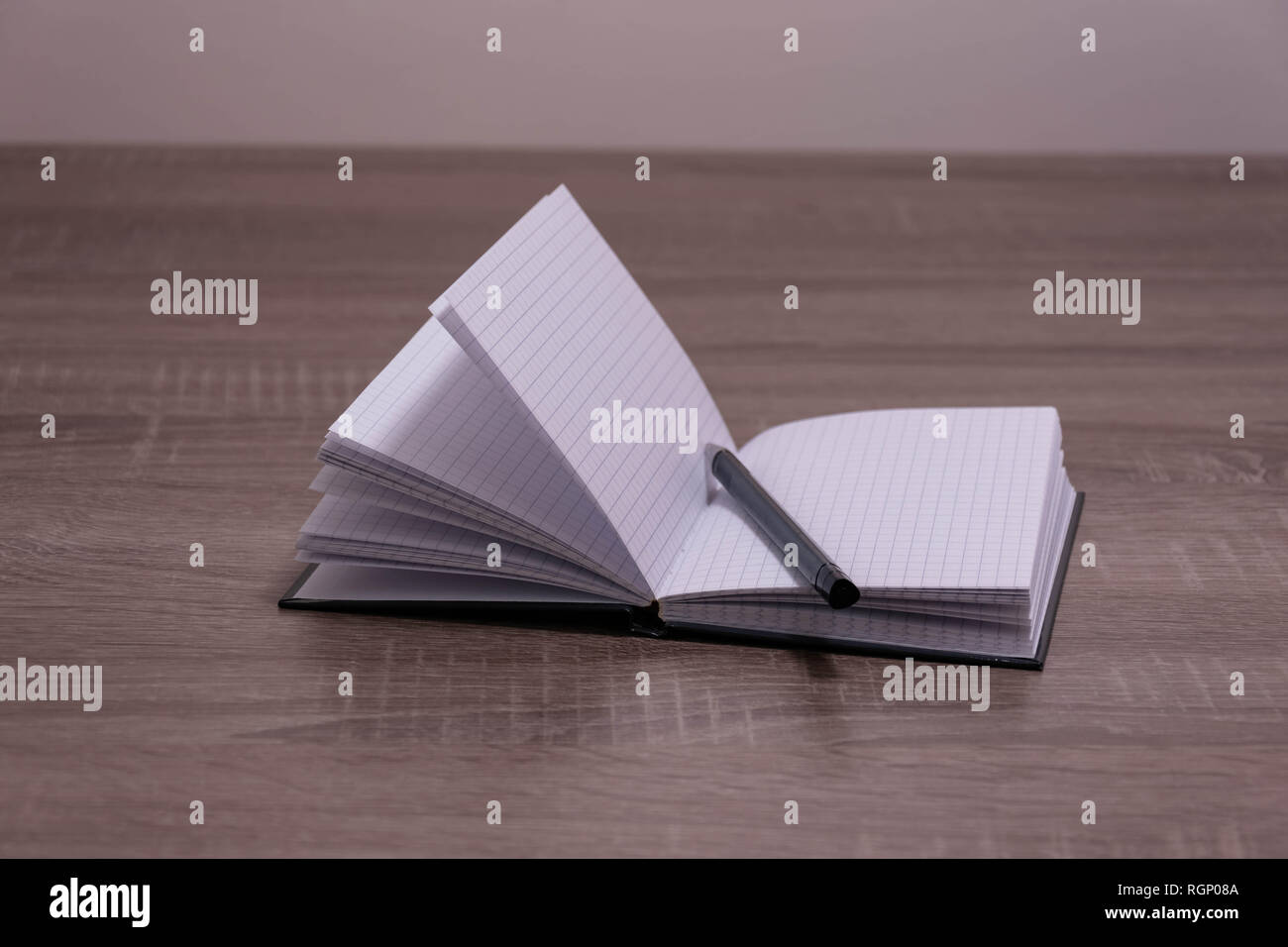 Opened notebook and pen on the brown desk. Stock Photo