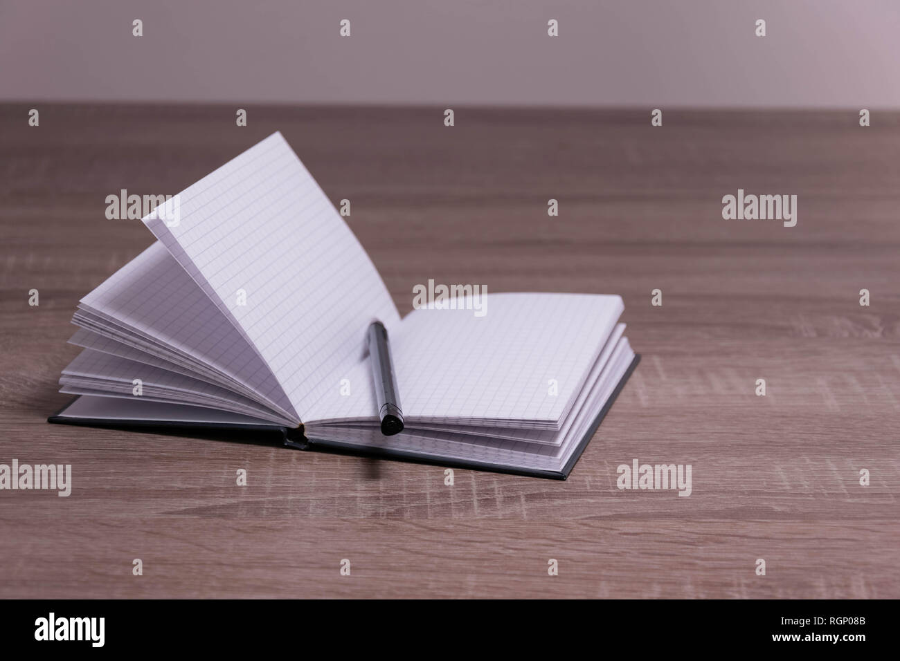 Opened notebook and pen on the brown desk. Stock Photo