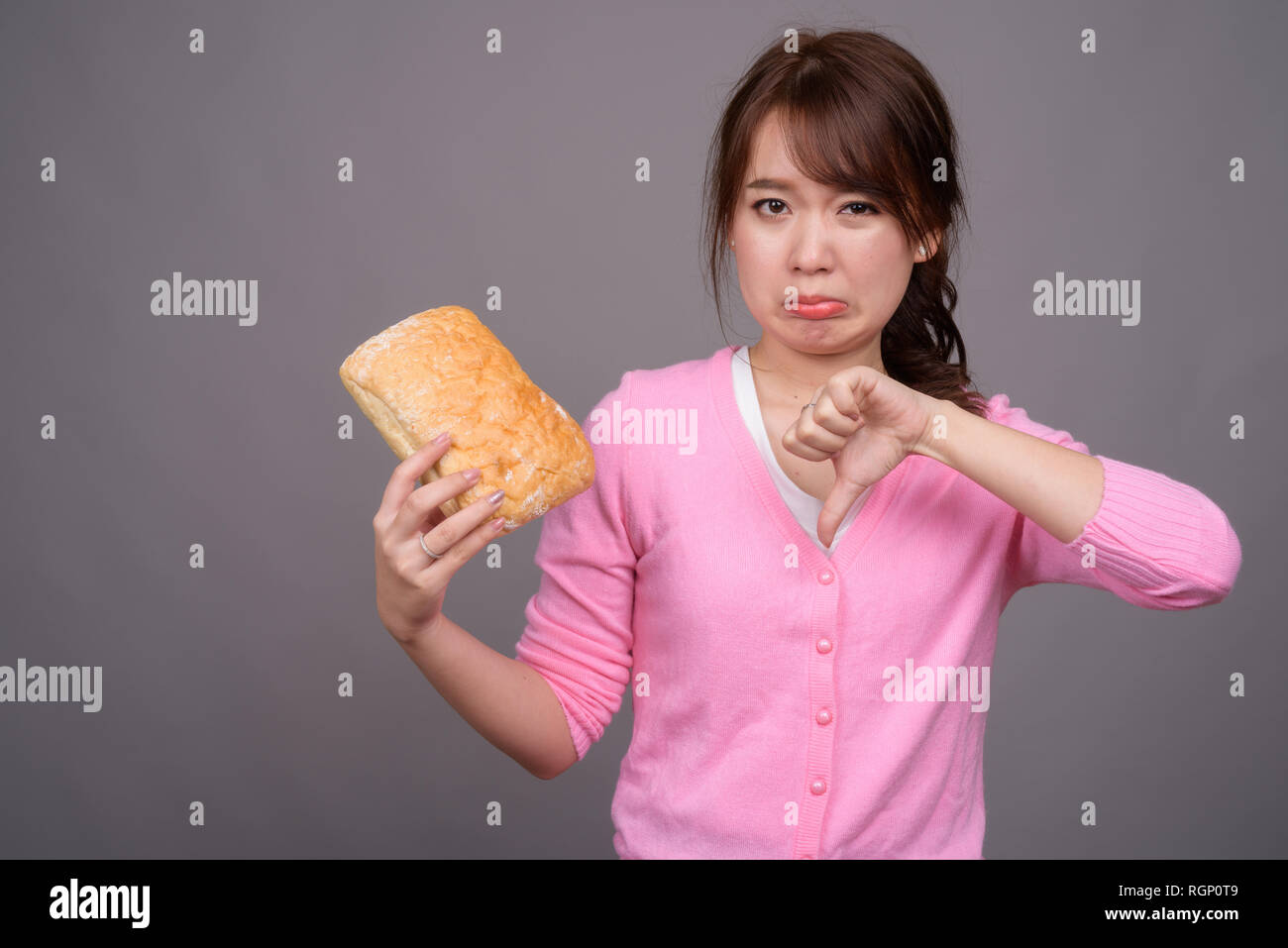 Young beautiful Asian woman holding piece of bread Stock Photo