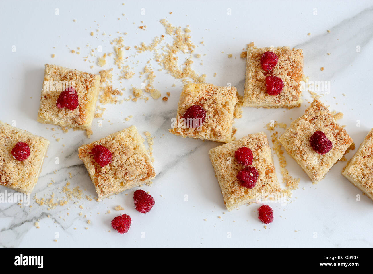 Sliced homemade cake with frozen raspberries on top on a light marble background, horizontal Stock Photo