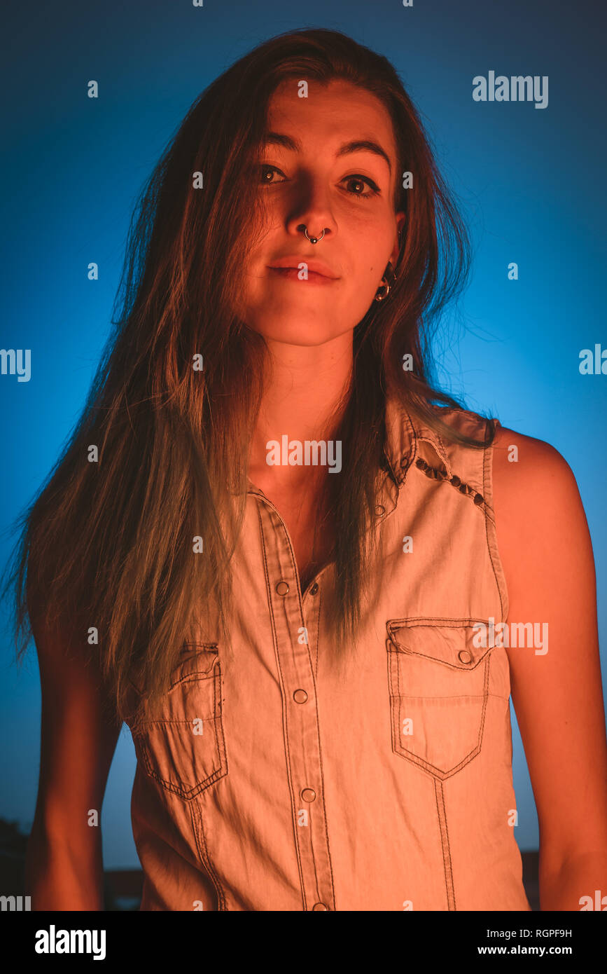 Charming young lady with piercing looking at camera in redness on blue background Stock Photo