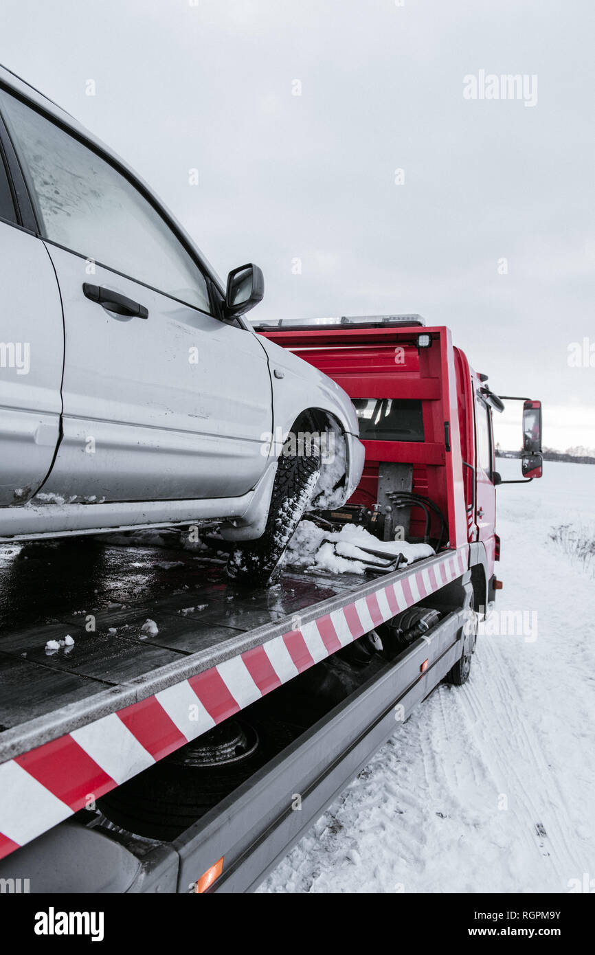 Broken automobile on breakdown truck on snow meadow in Vilnius, Lithuania Stock Photo