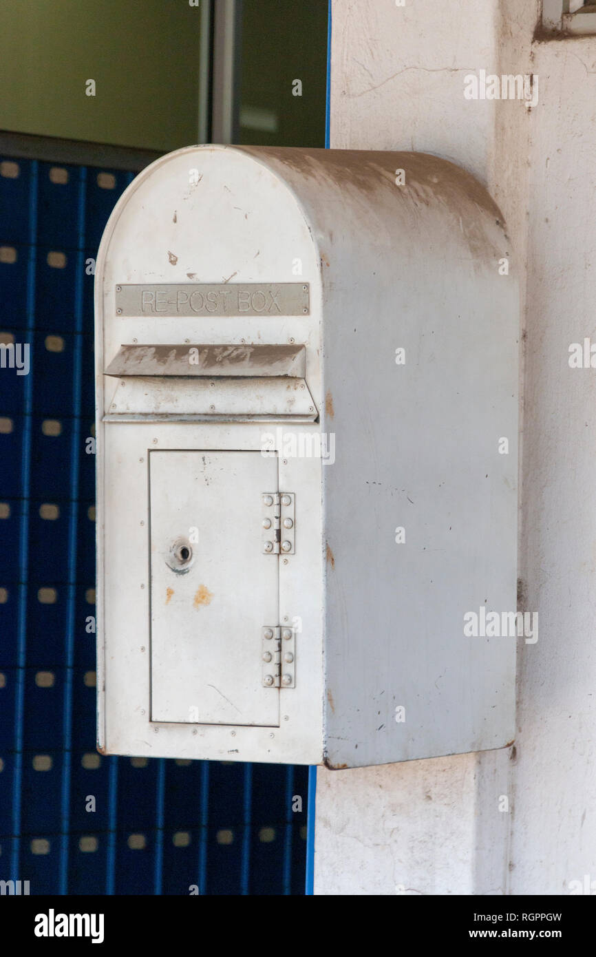 A close up front view of a white metal dirty post box that is bolted to ...