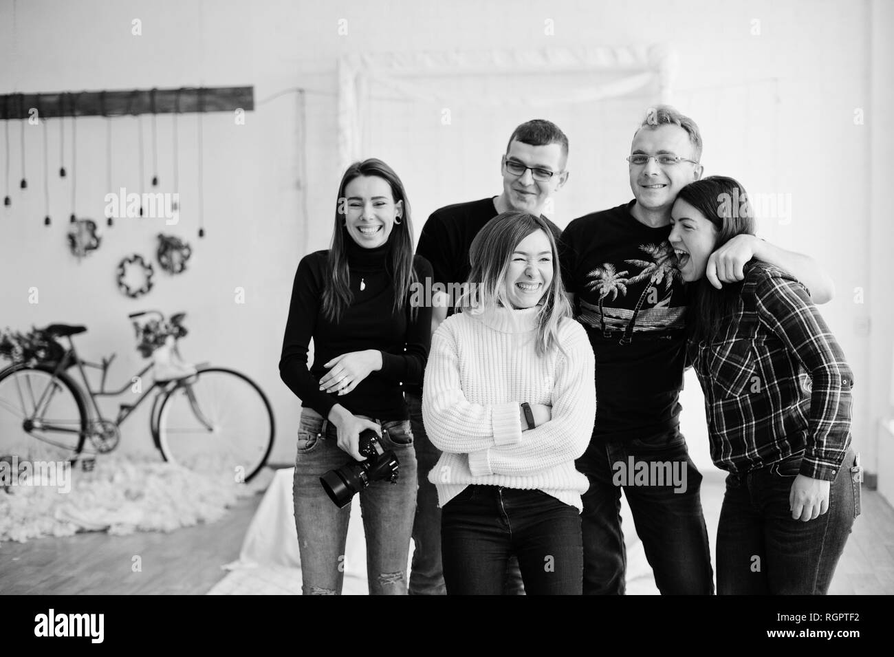 Group of five peoples, friends photographers and designers on studio shooting after hard work day. They happy and laughing. Stock Photo