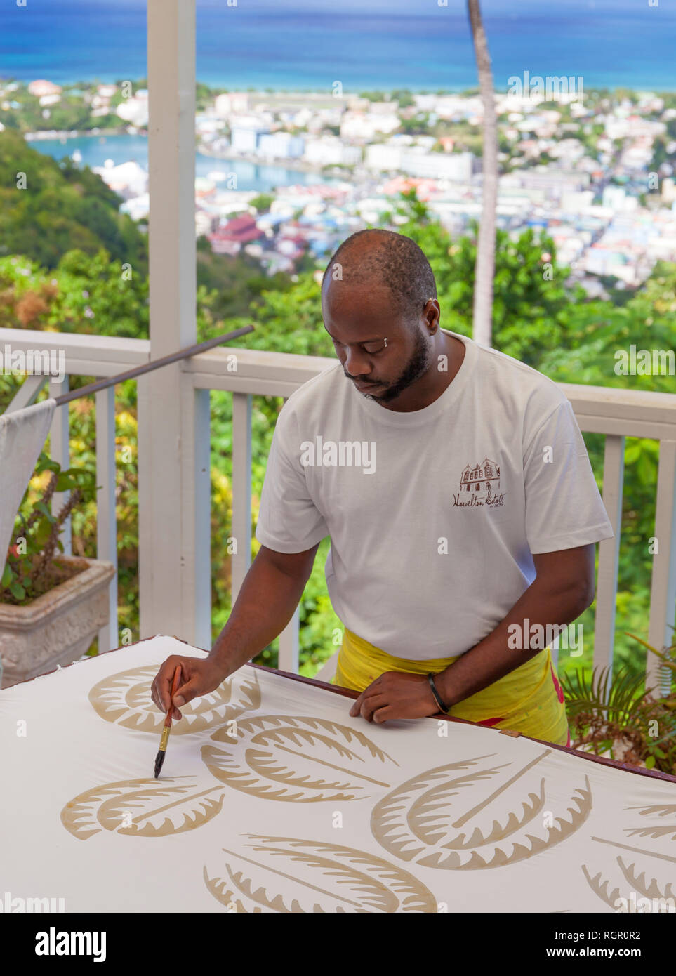 Man making Batik cloth by painting wax into the desired design. Howelton Estate, Saint Lucia, Caribbean. Stock Photo