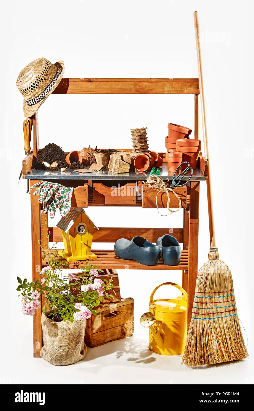 Wooden shelves with gardening accessories , nesting box, tools, flowerpots and a garden broom over white in a concept of the spring season Stock Photo