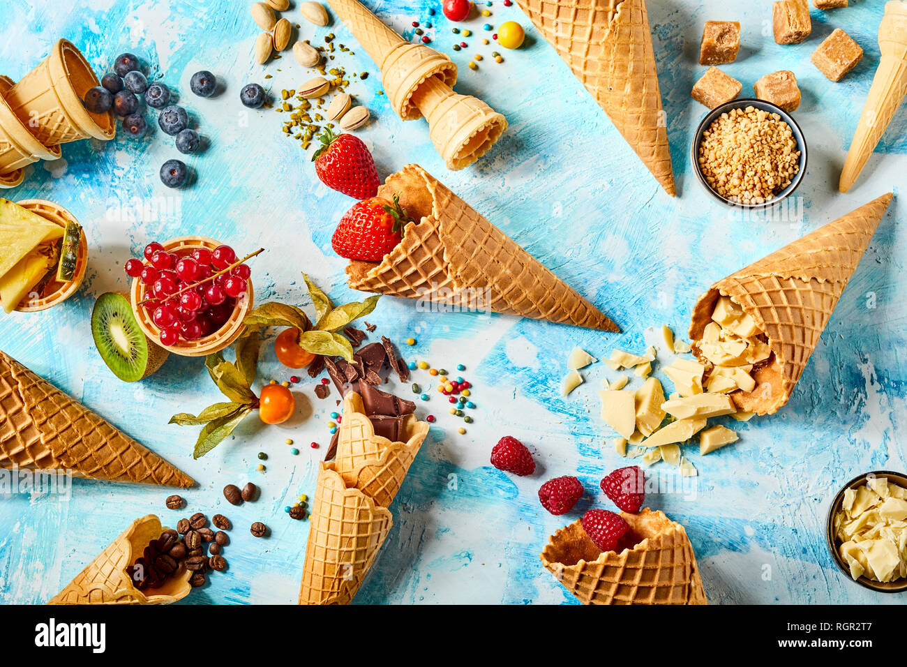 Crispy wafer cones filled with fruits and sweet ingredients against