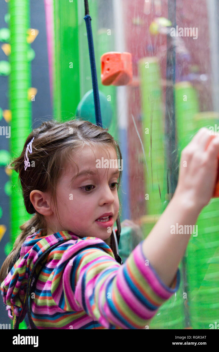Girl, six years old, on climbing wall at indoor climbing centre. Stock Photo