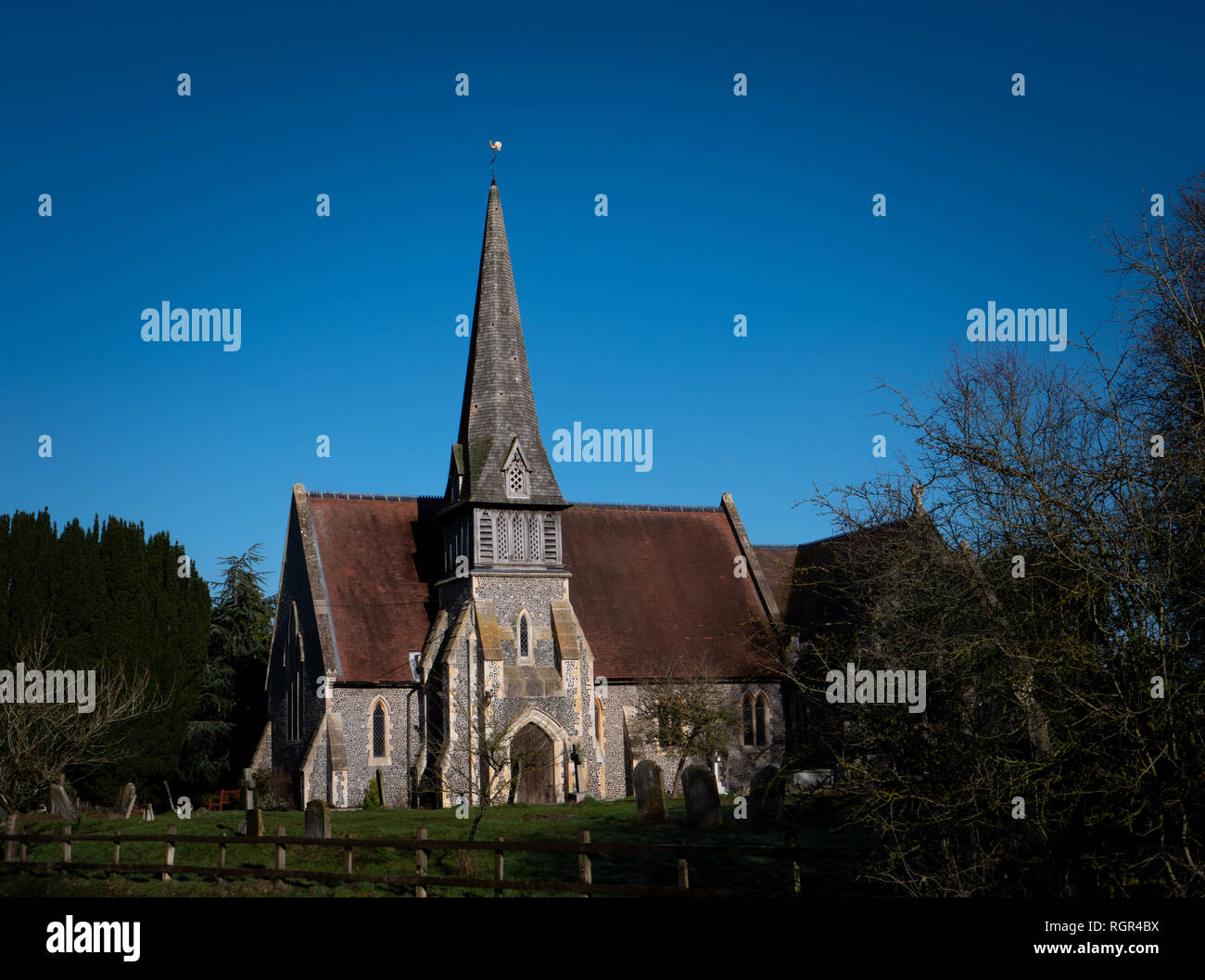 English country church with spire against blue sky. St James Barkham Stock Photo