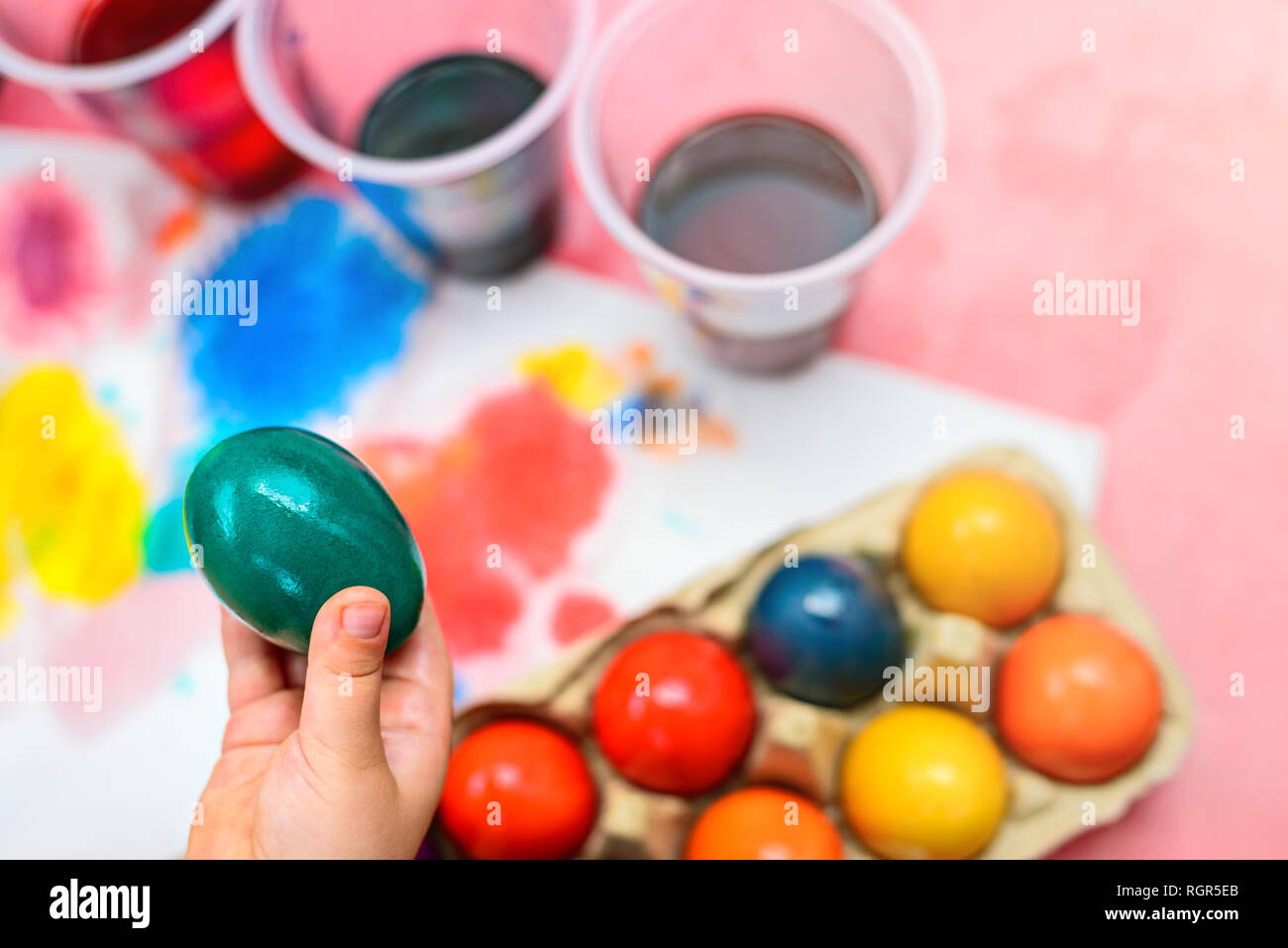 Child holding freshly boiled and colored Easter egg in his hand Stock Photo