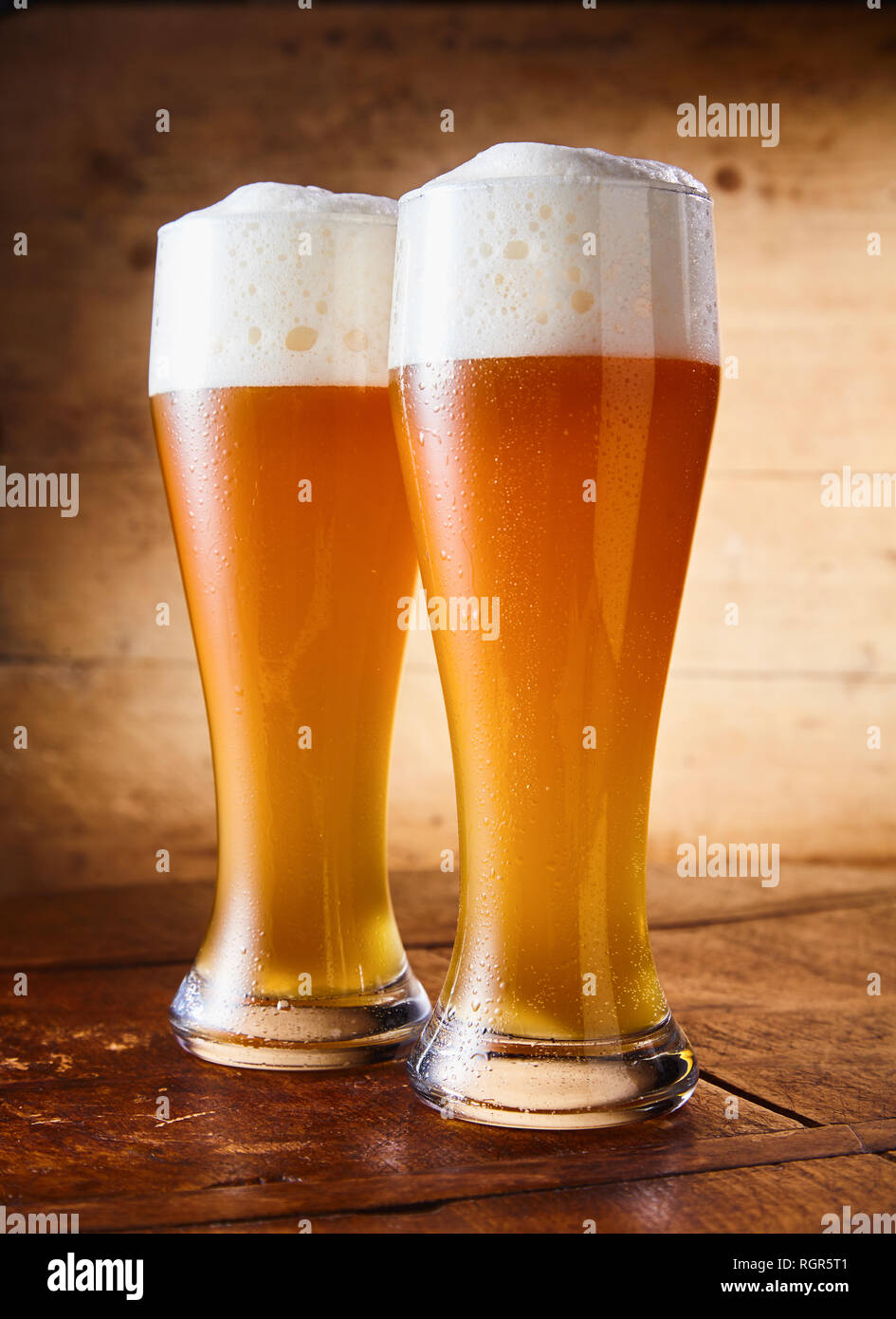 https://c8.alamy.com/comp/RGR5T1/two-tall-elegant-pint-glasses-of-cold-wheat-beer-with-a-frothy-head-on-a-wooden-bar-table-conceptual-of-oktoberfest-RGR5T1.jpg