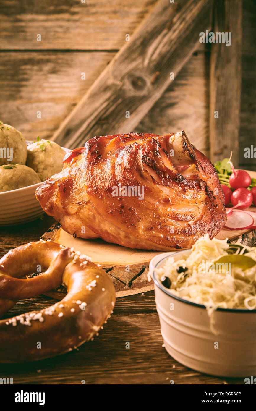 Gourmet glazed pork hock served with sauerkraut, dumplings and a pretzel in a rustic tavern Stock Photo