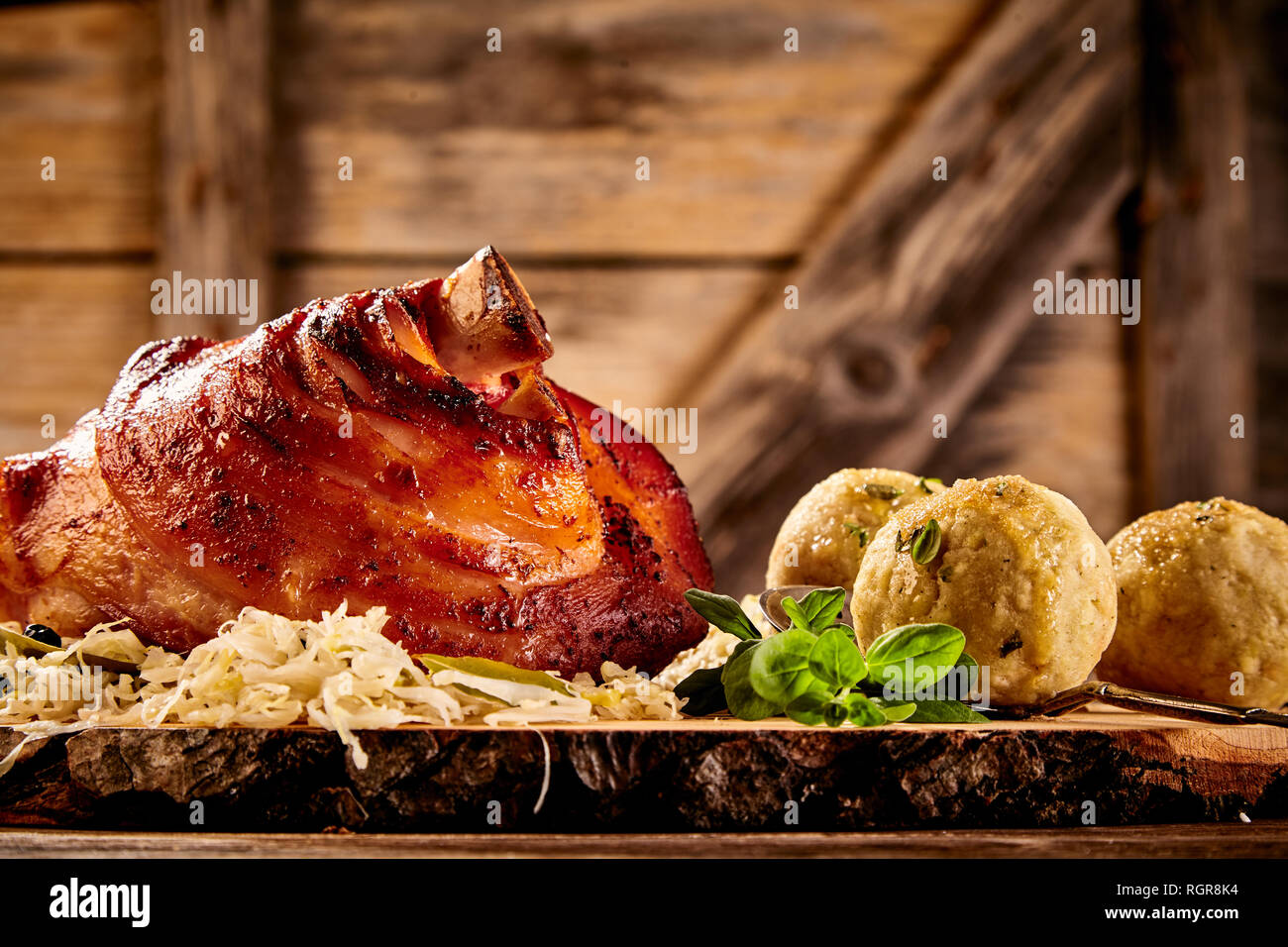 Crispy glazed roasted pork hock with crackling served with sauerkraut and savory dumplings in a low angle view Stock Photo