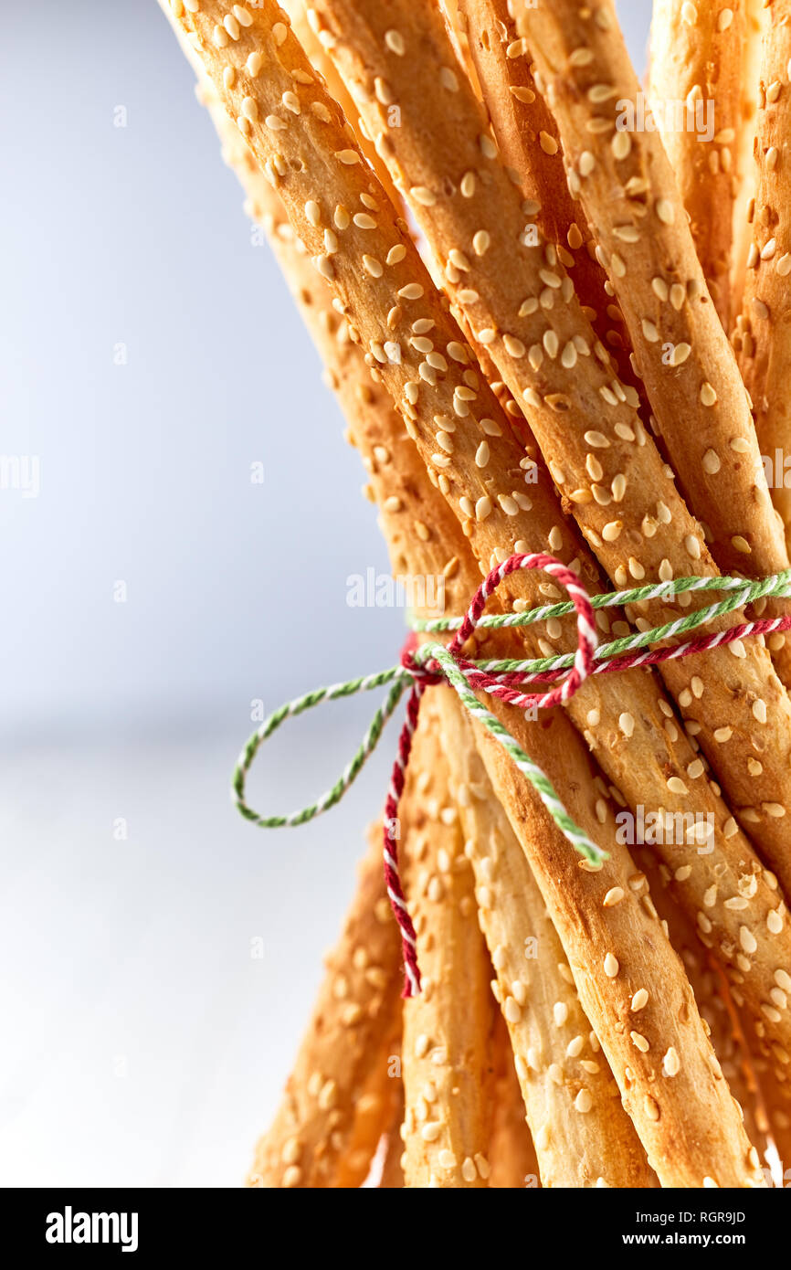 Closeup of savory sesame seed grissini breadsticks tied with string in