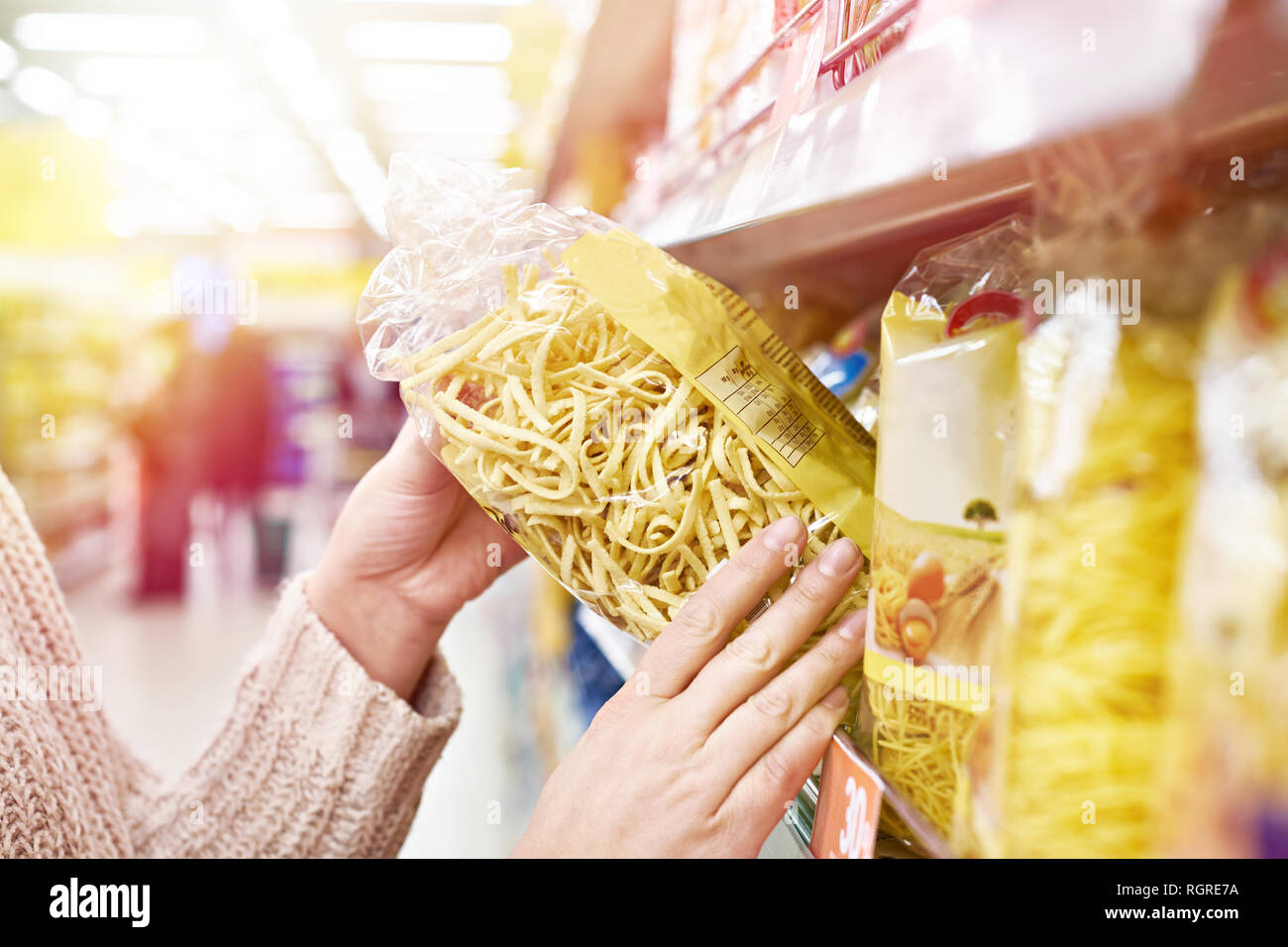 Pack of pasta in the hands of the buyer at the store Stock Photo