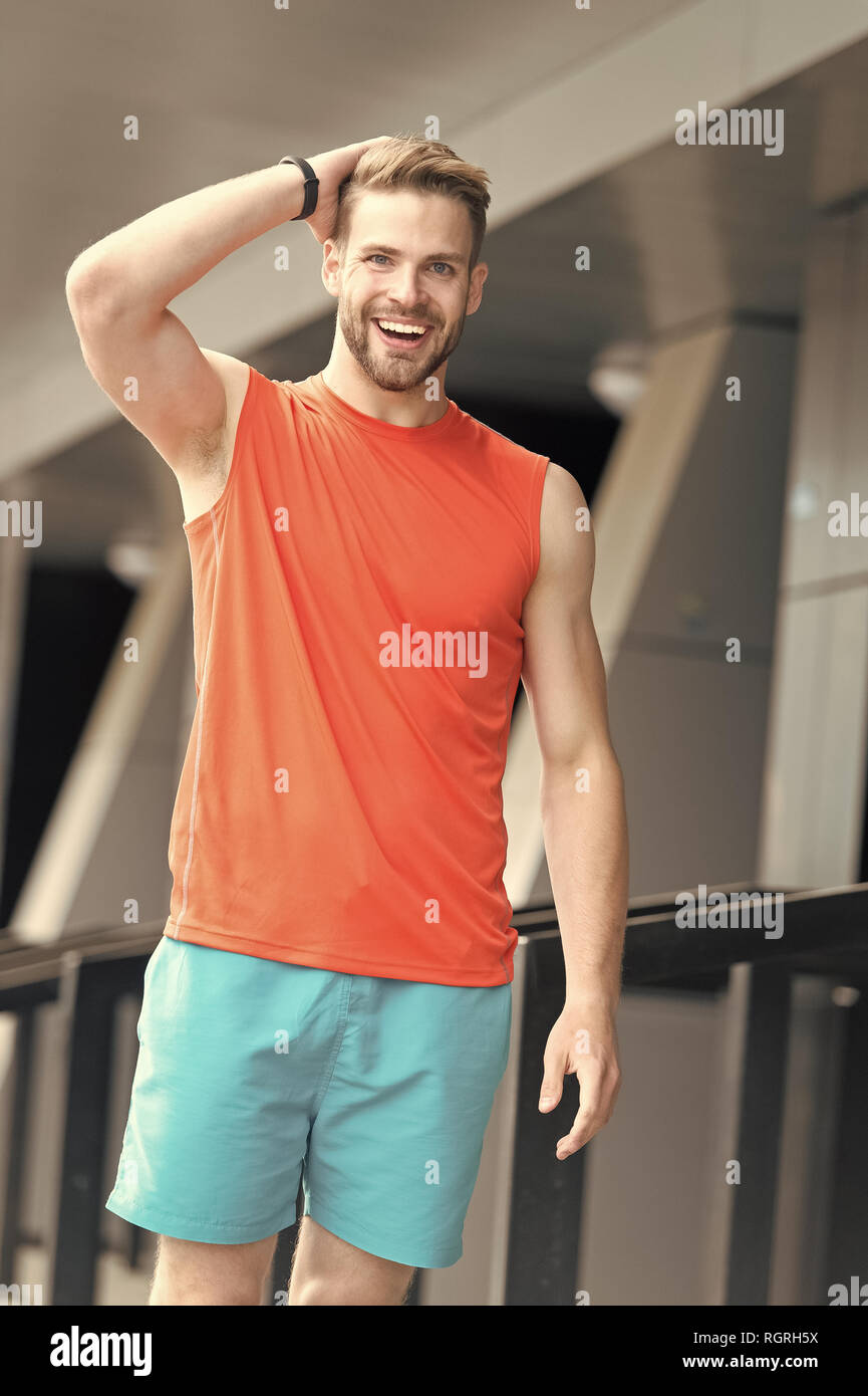 Man with bristle on smiling face in sporty wear, urban background. Sport  fashion concept. Man with beard or unshaven guy in stylish sport clothes.  Guy bearded and attractive cares about fashion Stock
