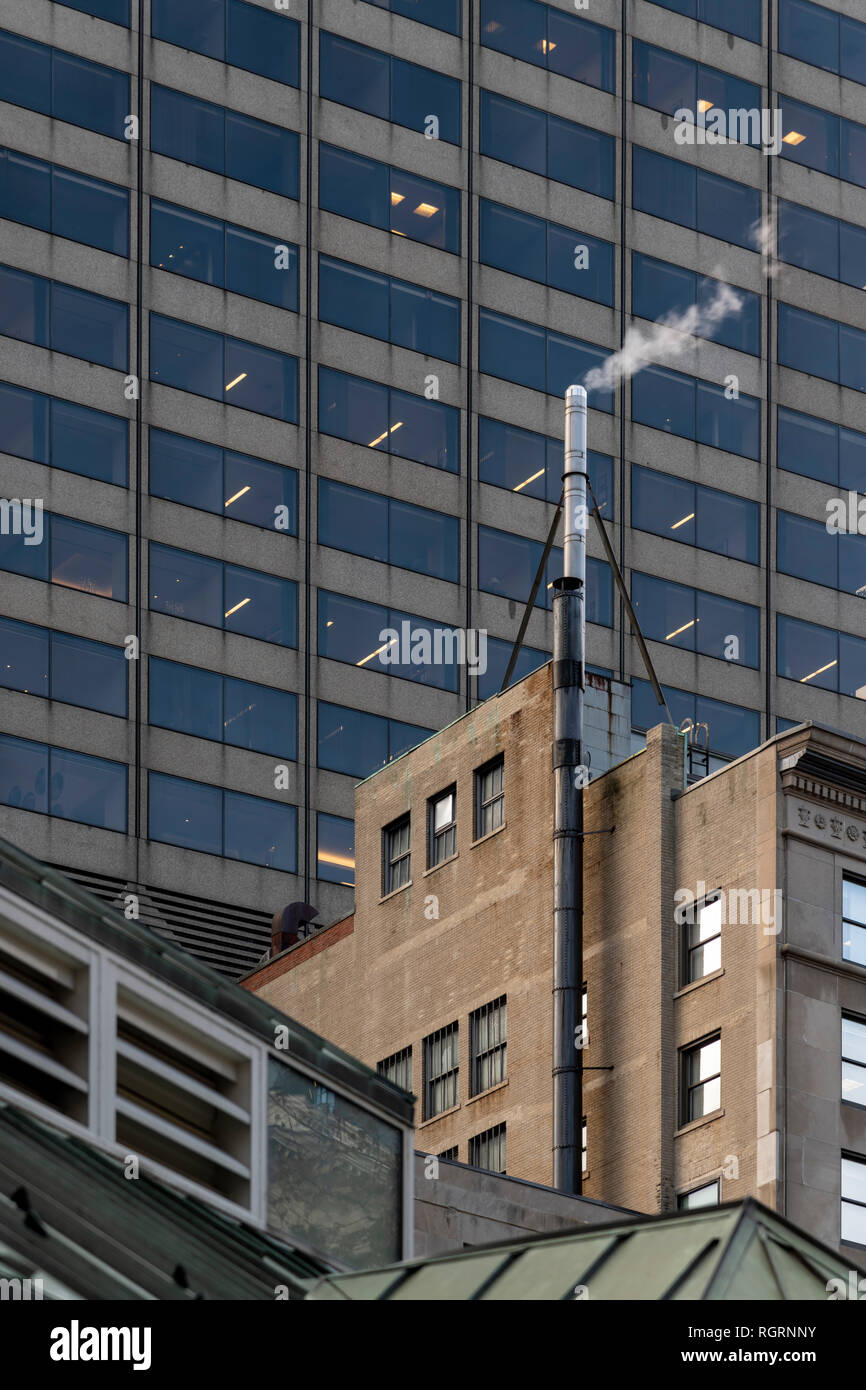Steaming chimney near Post Office Square at top of 24 Federal Street Building. Shot on freezing day in Boston, showing behind is One Federal Building. Stock Photo