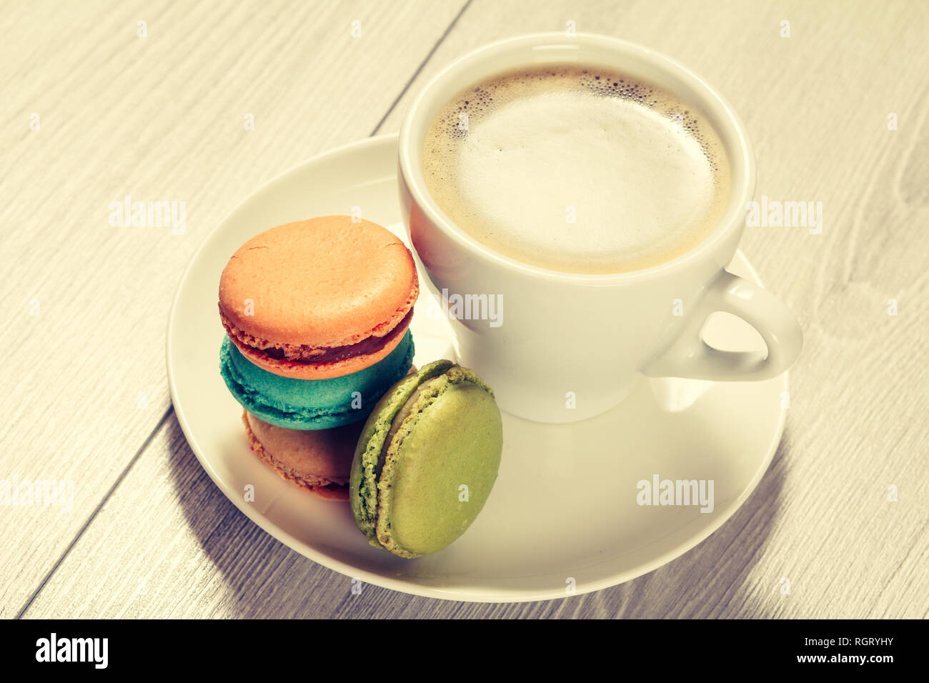 Cup of coffee and delicious macarons cakes of different color on white