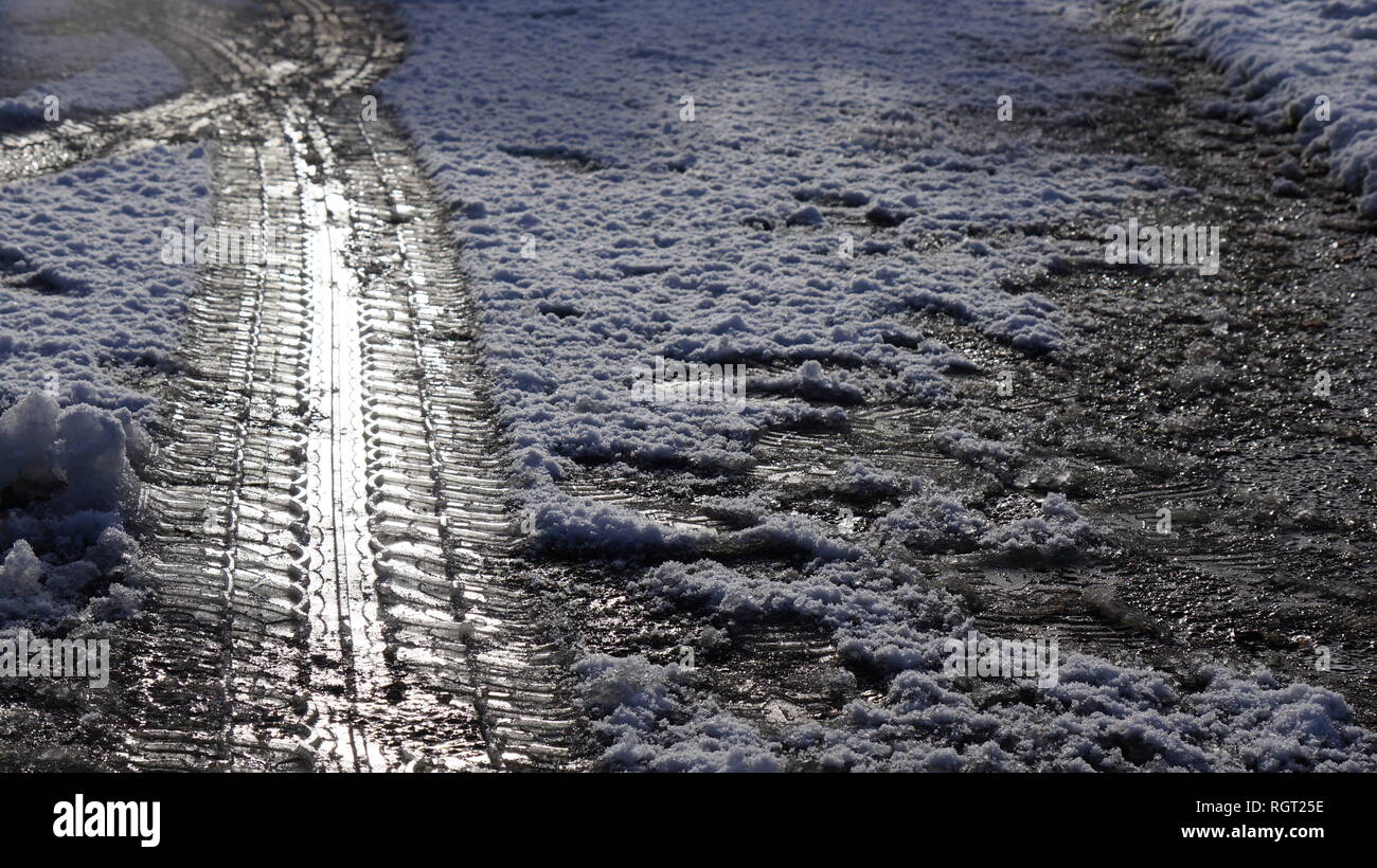 Tyre tread marks imprinted in the snow on an icy road in the winter. Stock Photo