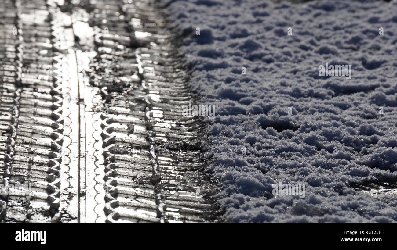 Tyre tread marks imprinted in the snow on an icy road in the winter. Stock Photo