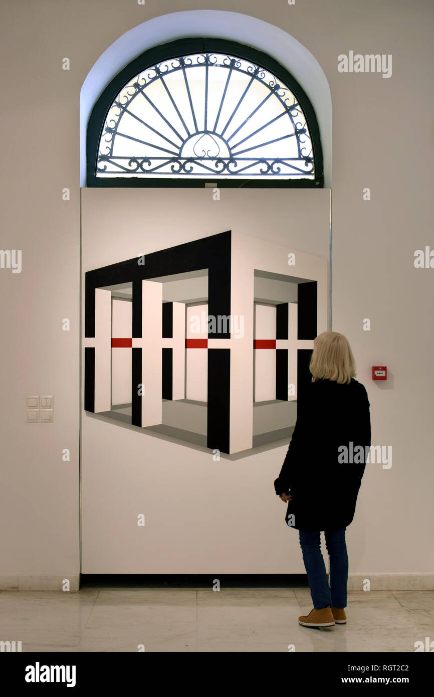 ATHENS, GREECE - DECEMBER 7, 2018: Woman looking at modern geometric painting by Opy Zouni (1941 - 2008) at Municipal Art Gallery. Stock Photo