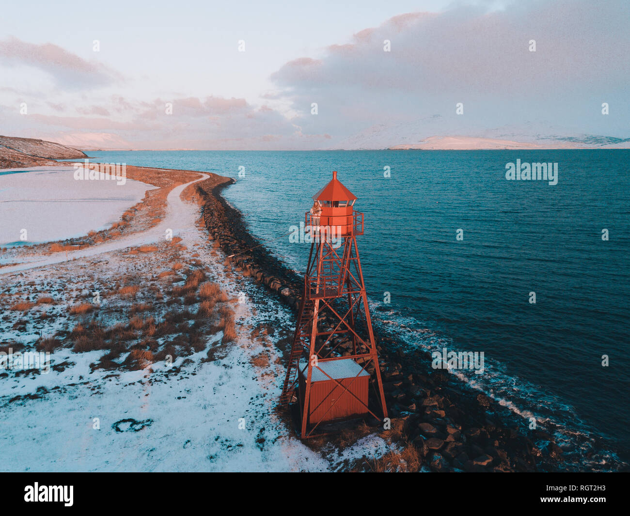 Small lighthouse standing on snowy Arctic coast near cold waving sea Stock Photo