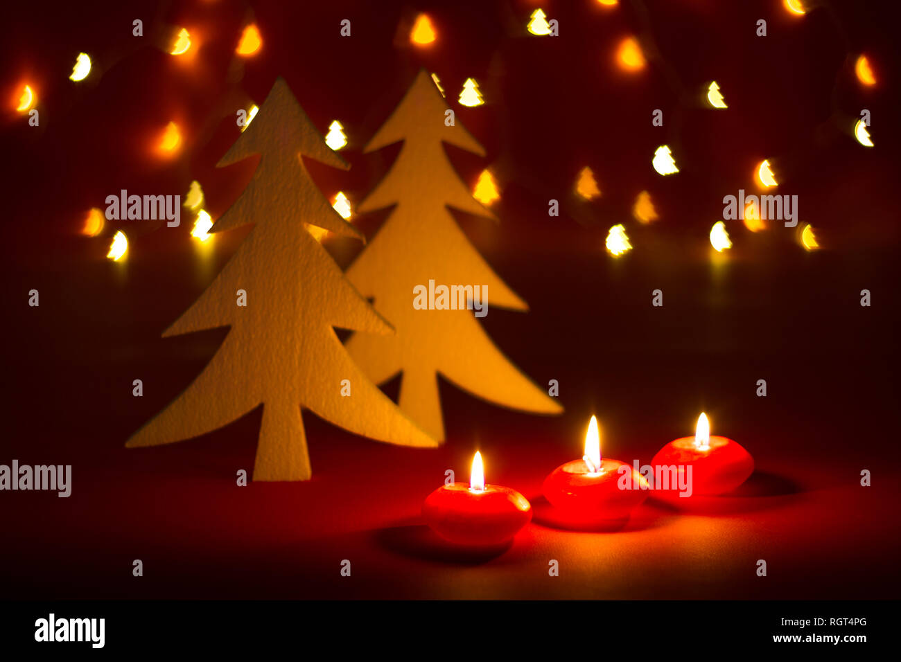 Christmas candles and ornaments over red dark background shaped bokeh with lights Stock Photo