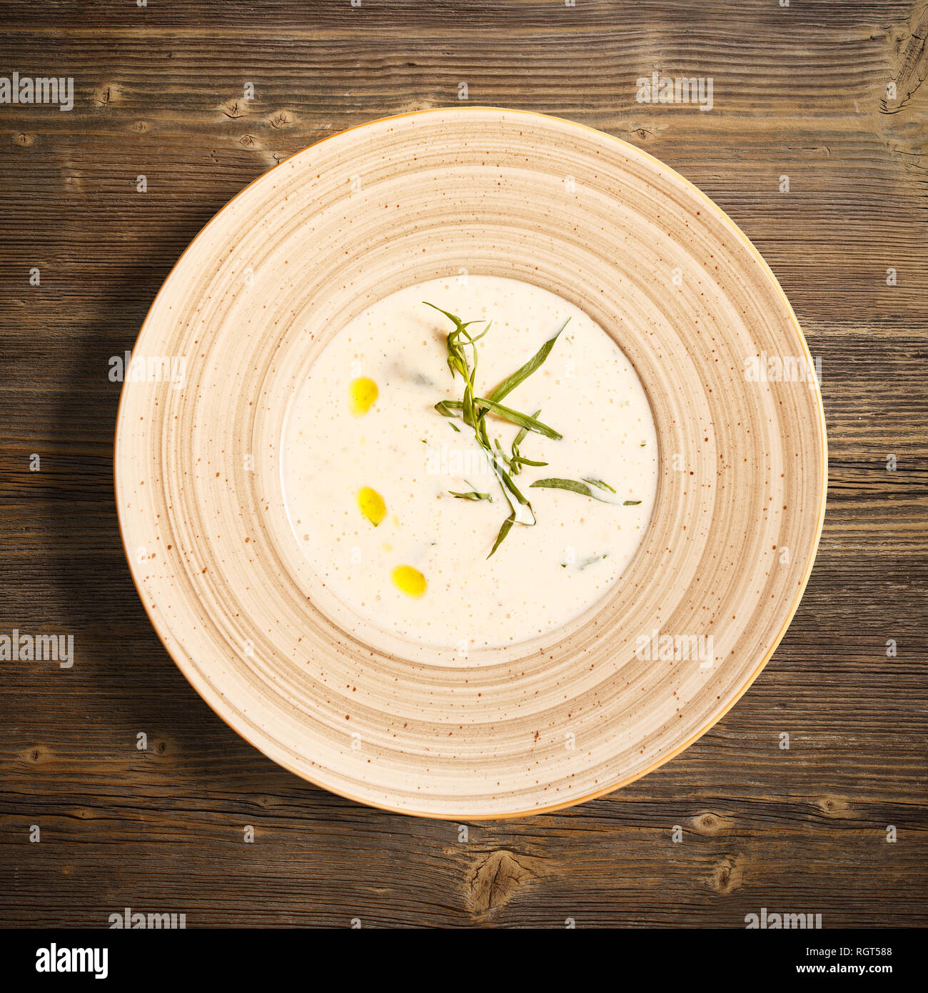 Flat lay of roasted potato cream soup with tarragon on wooden background Stock Photo